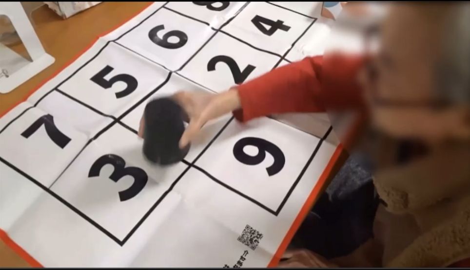 机に置いたシートの数字を、手でタッチする様子