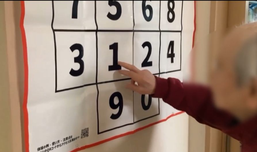 壁に貼ったシートの数字を、指でタッチする様子